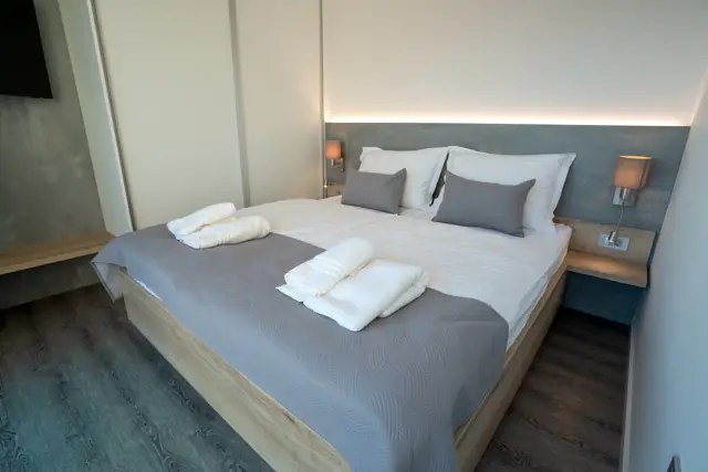 Bedroom with wooden bed frame, ambient lighting and wall-mounted TV
