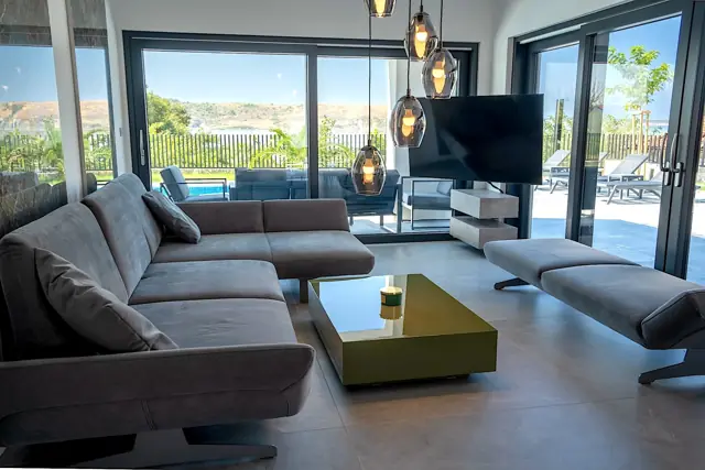 Open-plan living room with sculptural pendant lights and pool view