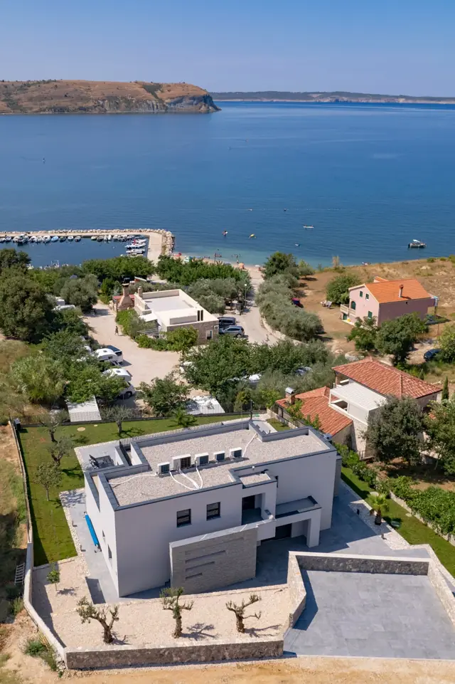 Aerial view of the villa and garden facing the bay and beach