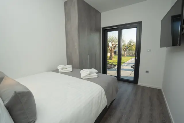 Bedroom with garden view, wardrobe and wall-mounted TV